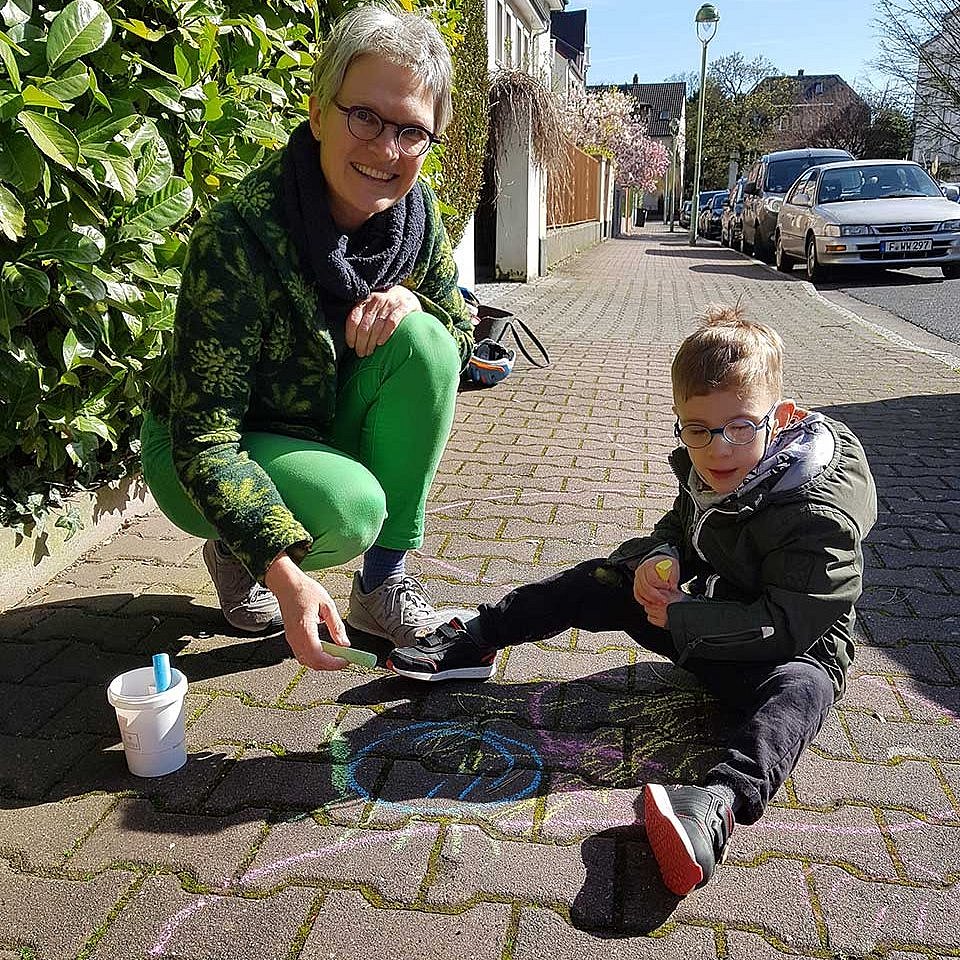 Tanja Misof und Leon malen mit Kreide auf den Gehweg