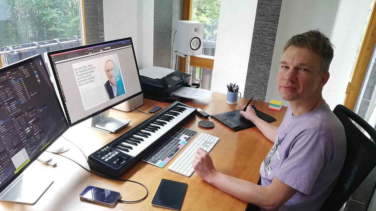 Andreas Croonenbroreck vor zwei Monitoren, mit Grafik-Tablet, zweit Tastaturen und einem Midi-Keyboard