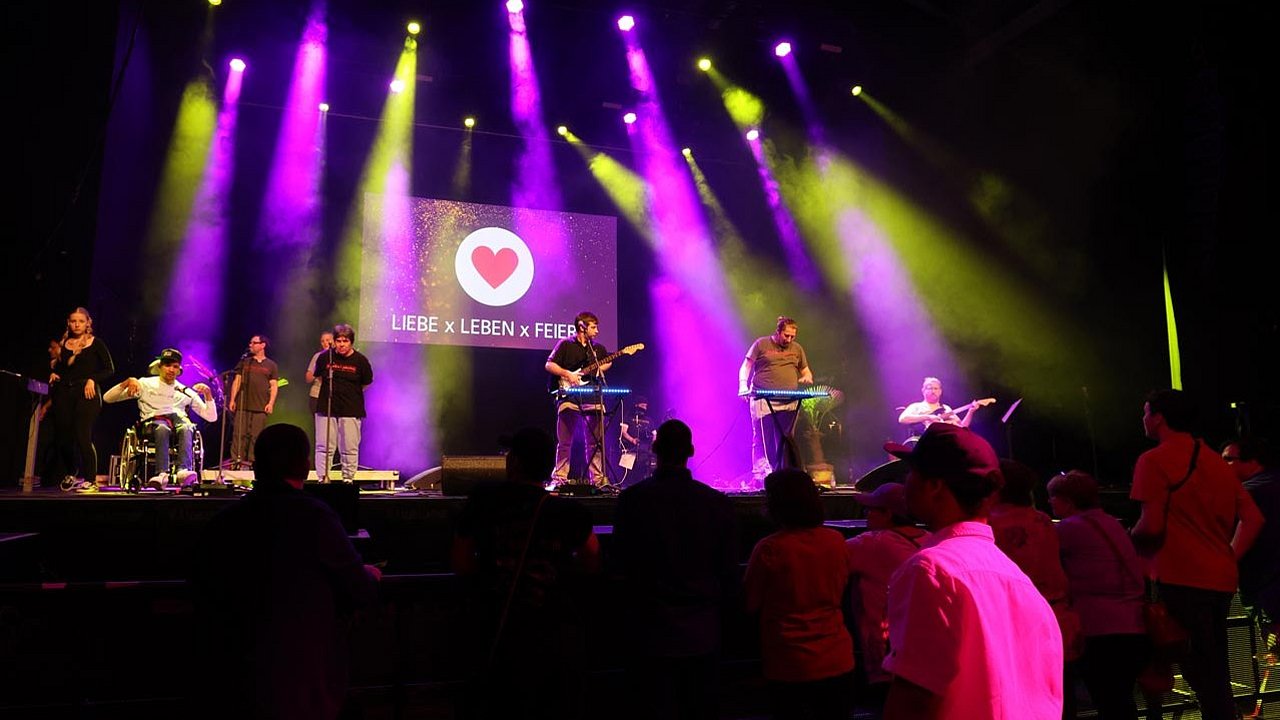 Auf der Bühne spielt die Band „Ruhestörung". Insgesamt waren 247 Party-Gäste im Wiesbadener Schlachthof. Die Bühne ist in lila und gelb getaucht. 