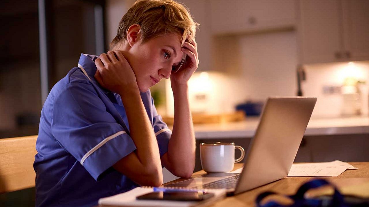 Müde Frau, die nachts zu Hause am Laptop arbeitet oder lernt