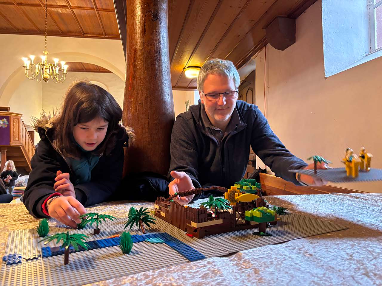 Pfarrer Stefan Mendling und ein Mädchen mit einer Legokrippe