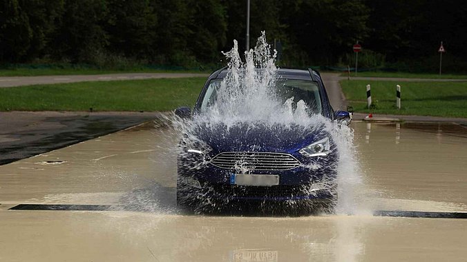 ein blauer Ford fährt durch eine Fontäne