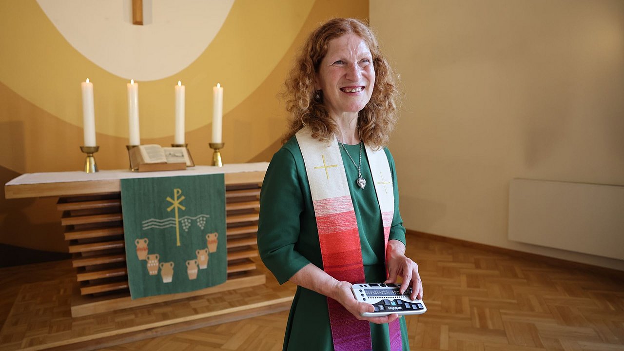 Brigitte Buchsein steht während des Gottesdienstes mit ihrem Braille-Lesegerätes vor dem Publikum