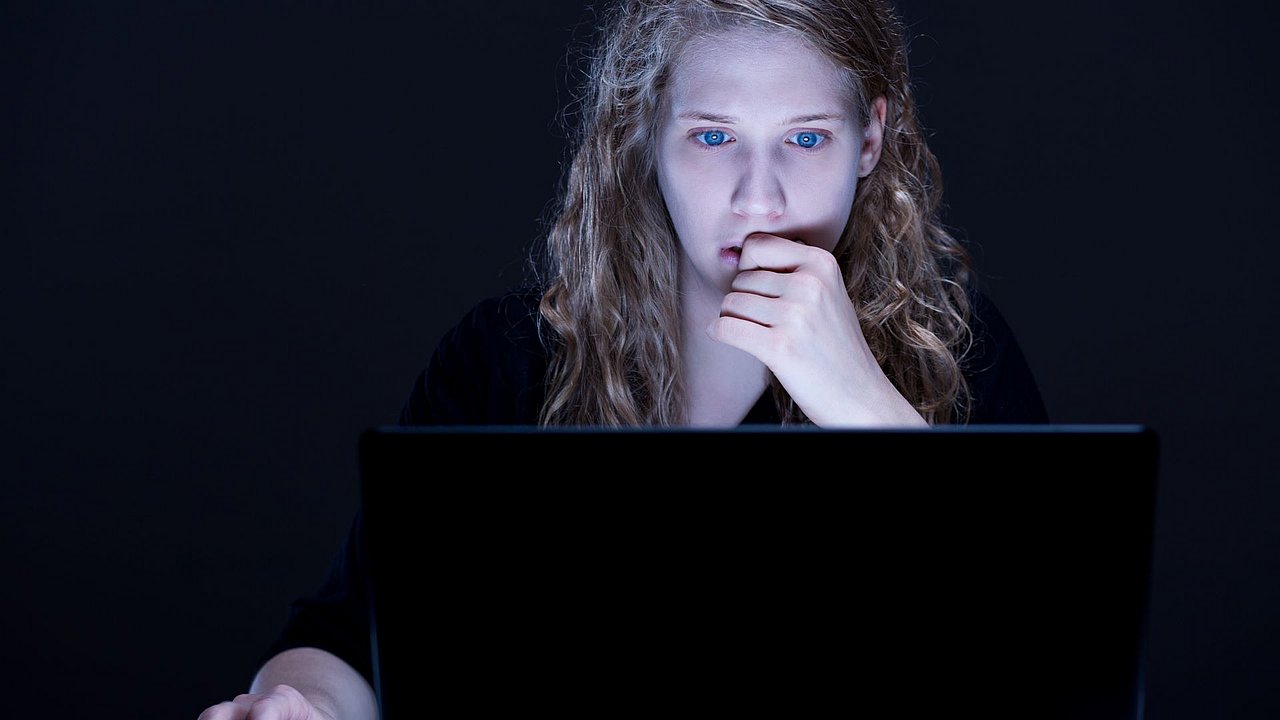Frau sitzt im Dunkeln vor einem Laptop