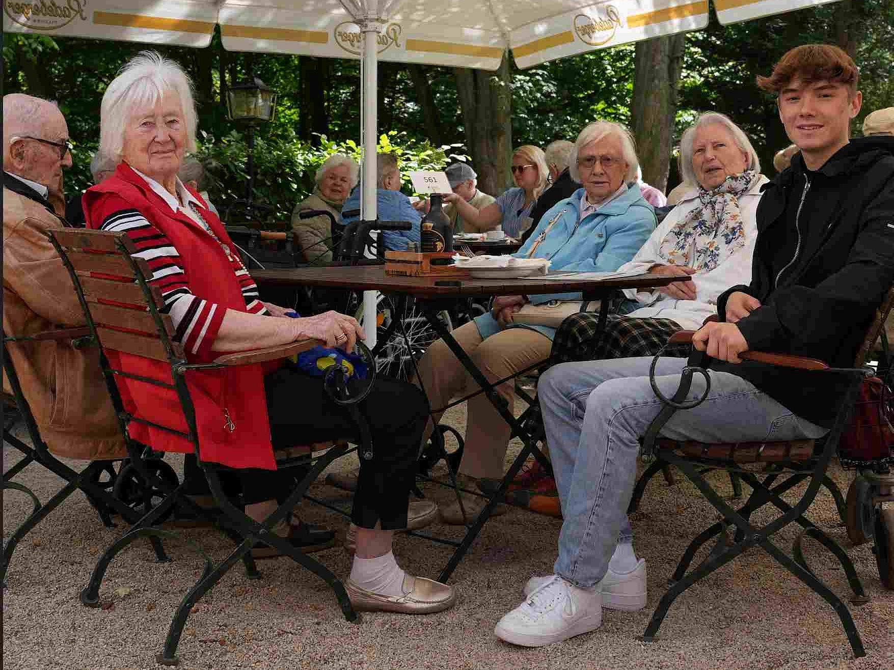 Max Löser schlüpft in die Rolle eines Altenbetreuers und sitzt mit Bewohnerinnen und Bewohnern des Haus Emmaus am Tisch.