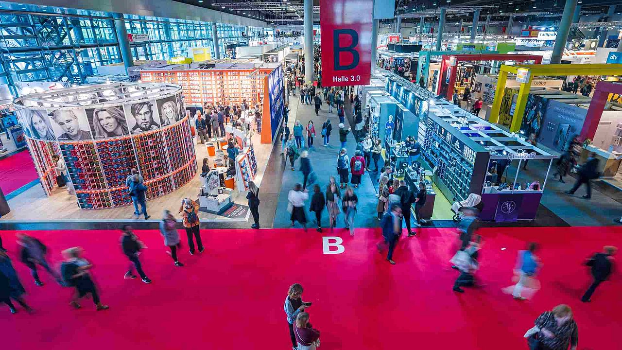 Menschen laufen in einer Halle der Buchmesse Frankfurt umher