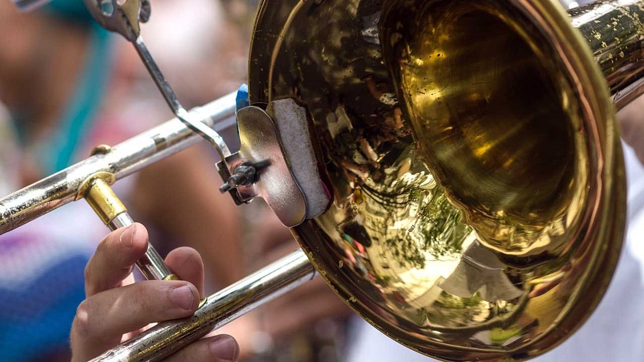 Hand eines jungen Mannes, der das Musikinstrument Posaune spielt