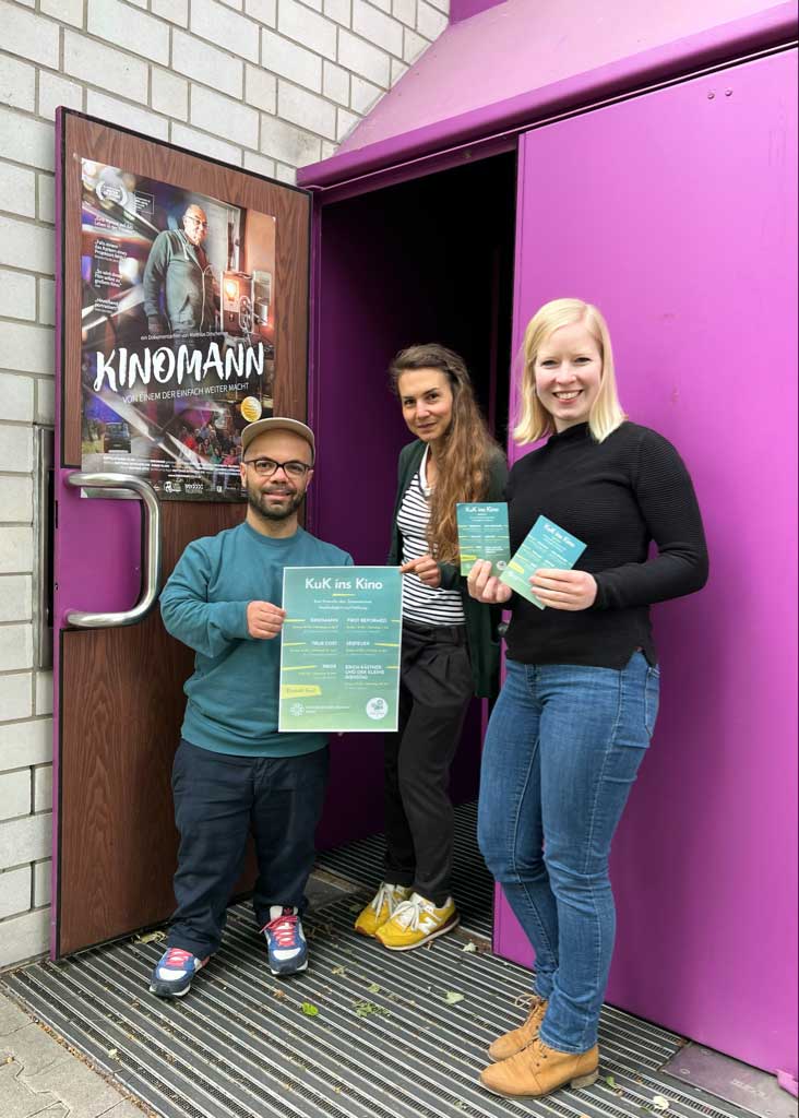 Drei Personen zeigen Flyer und Programm vom KuK - dem Programmkino in Mainz